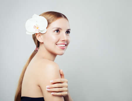 Happy young woman with white orchid flower portraitの写真素材