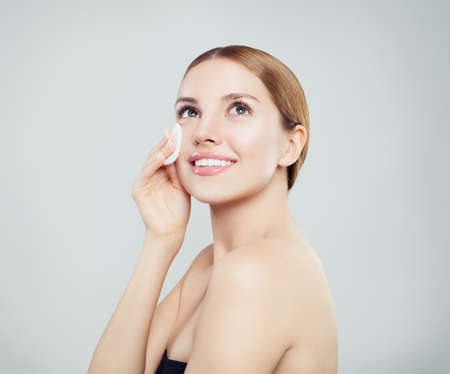 Beauty portrait of a young attractive woman cleaning her face with a cotton padの写真素材