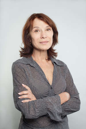 Smiling mid adult business woman with crossed arms on whiteの写真素材