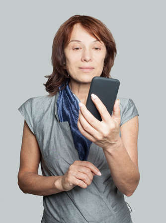 Mature woman using smartphone and chattingの写真素材