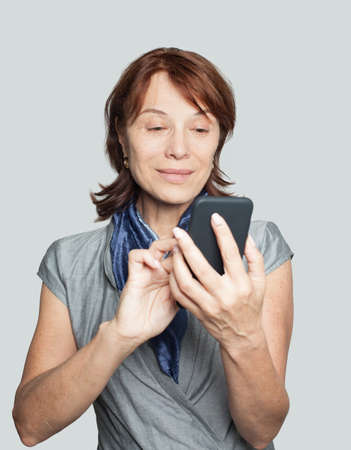 Smiling mature female with smartphoneの写真素材