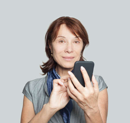 Mature woman using smartphone on whiteの写真素材