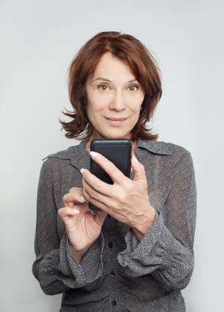 Smiling mature woman with cell phoneの写真素材