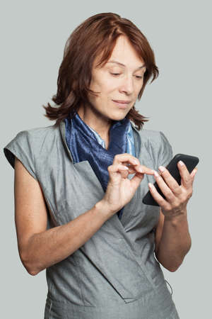 Mature woman with smartphone texting coworker. Business woman cell phoneの写真素材