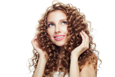 Cheerful blonde woman touching her hair her hand and looking up. Haircare conceptの写真素材