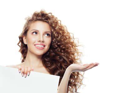 Friendly woman showing open hand and white empty paper boardの写真素材