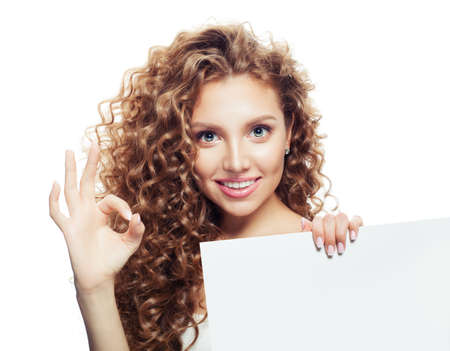 Happy young woman showing ok sign and holding empty paper board isolated on white backgroundの写真素材