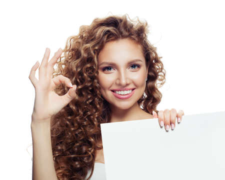 Cute girl showing ok sign and holding empty paper board isolated on white backgroundの写真素材