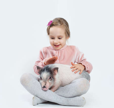 Happy child girl with pig. Child and petの写真素材