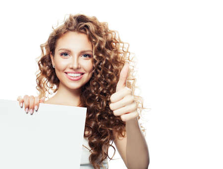 Cheerful smiling woman showing thumb up and holding white empty paper board isolatedの写真素材