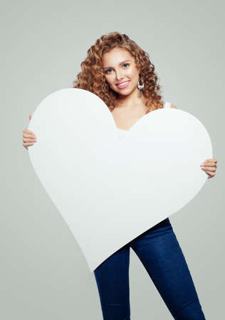 Happy woman with white empty paper heart banner  with copy space.の写真素材
