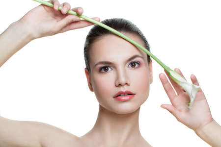 Young spa woman with white lily flower isolated on white background. Beautiful female model face with healthy clear skin. Facial treatment, cosmetology, beautyの写真素材