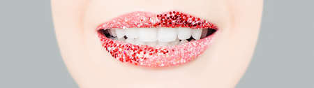 Perfect smile with red lips and white healthy teeth. Female mouth with glitter lipstick makeupの写真素材