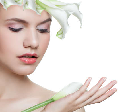 Floral spring portrait of young woman with white flower isolated on white background. Beautiful female model face with healthy skin. Facial treatment, cosmetology, beauty, skin care and spa conceptの写真素材