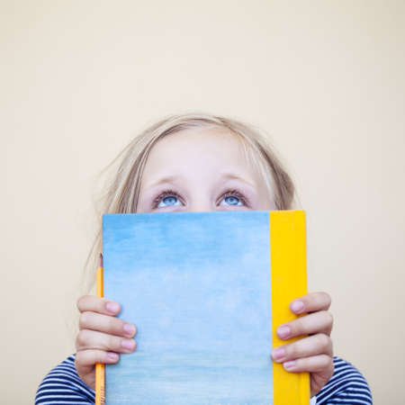Young girl with book looking up on  with copy spaceの写真素材