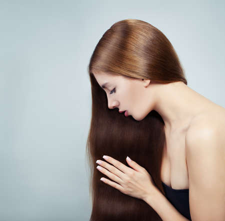Young perfect woman with long shiny silky hair on whiteの写真素材