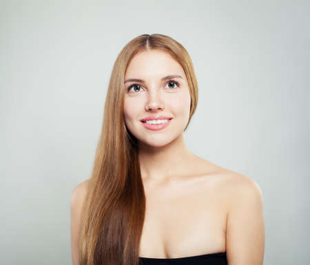 Beautiful woman face. Perfect girl with healthy hair and clear skin smiling and looking upの写真素材