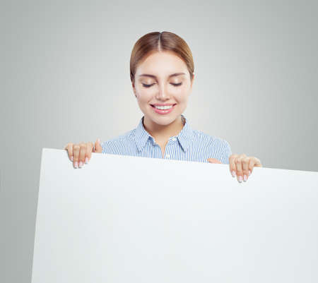 Young smiling woman showing white empty paper banner  with copy space.の写真素材