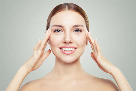 Beautiful woman touching her face in eyes area. Facial treatment, face lifting, anti aging and skin care concept.の写真素材