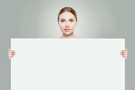 Healthy woman and big white empty paper board background in her handsの写真素材