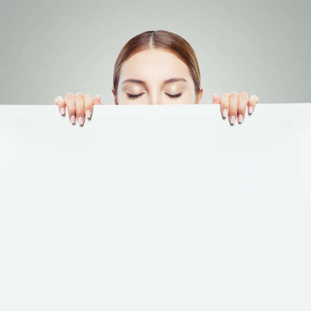 Young woman looking down and showing white empty paper card background with copy space for advertising marketing or product placementの写真素材