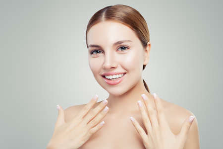 Excited woman with healthy clear skin, cute smile and french manicure hand. Cosmetology offer conceptの写真素材