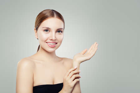Cute gitl smiling and holding empty open hand. Facial treatment, face lifting, anti aging and skin care cosmetics concept.の写真素材