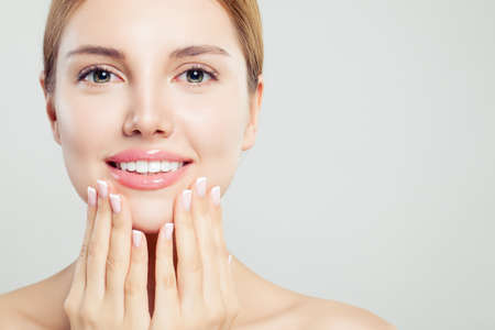 Beautiful face with pink glossy lips and manicured hands with french manicure nails, closeup portraitの写真素材