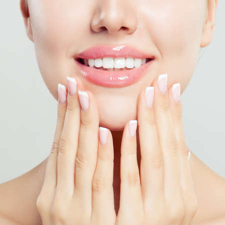 Beautiful female lips with glossy pink makeup and manicured hands with french manicure nails, closeup portraitの写真素材