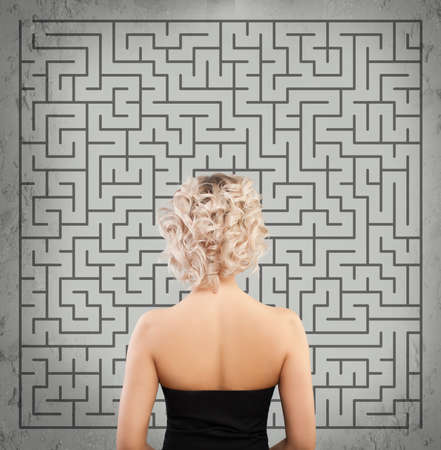 Woman standing in front of maze or labyrinth entrance about to make a decision and finding escape. Start up, problem and solution conceptの写真素材