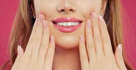 Beautiful woman smiling and showing her hand with manicure nails with natural pink nail polish. Makeup lips with pink color glossy  lipstickの写真素材