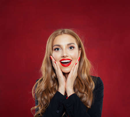 Surprised woman with opened mouth on red background. Happy girl having fun. Positive emotionsの写真素材