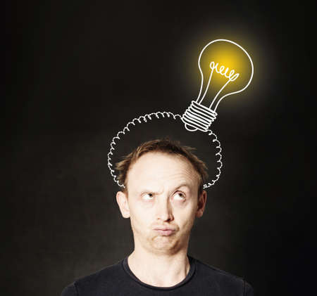 Idea concept. Man thinking on blackboard background with light bulb. Brainstorm and ideaの写真素材