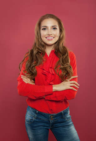Portrait of young smiling woman on pink background. Successful girl with arms crossed portraitの写真素材