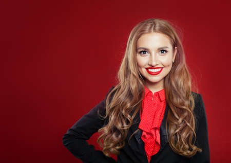 Portrait of young beautiful confident businesswoman in suit. Girl smiling and looking at camera on red background with copy spaceの写真素材