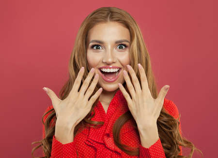 Excited surprised woman with natural makeup, curly ginger hair and manicured hand on colorful bright pink background. Happy girl, positive emotion. Expressive facial expressionの写真素材