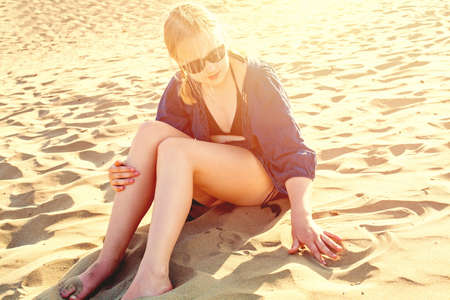 Young girl drawing heart on sea sand. Happy holiday conceptの写真素材