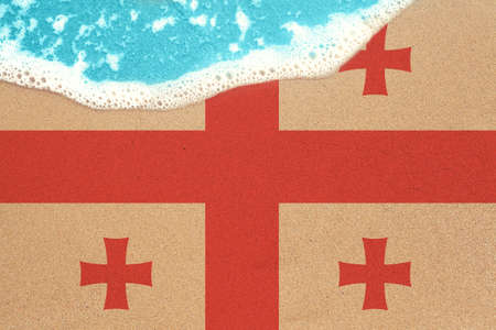 Sea wave on the sunny sandy beach with flag Georgia. View from top on surf.の写真素材