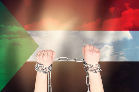 Two hands shackled a metal chain  of the Sudan flag. Freedom conceptの写真素材