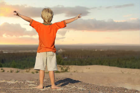 Kid Boy looking the sunrise on the sand mountainの写真素材