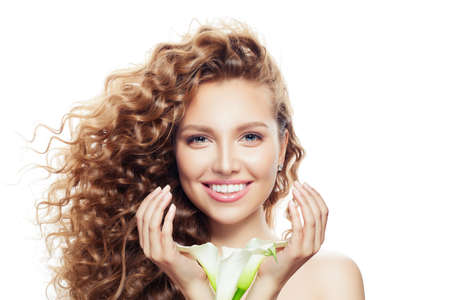 Happy young woman with curly hair isolated on white. Beautiful model with clear skin and flowers in hands portraitの写真素材