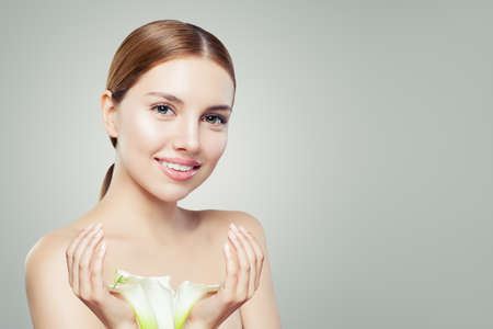 Beautiful woman face. Healthy model with clear skin and flowers. Skincare and facial treatment conceptの写真素材