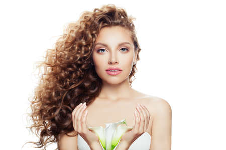 Young perfect woman with long curly hairstyle, healthy skin and lily flower in her hands isolated on white backgroundの写真素材