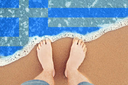 Feet on sandy beach with flag Greece. Top View on sea Waveの写真素材