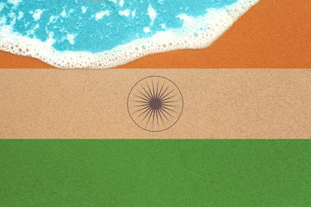 Sea wave on the sunny sandy beach with flag India. View from top on surf.の写真素材