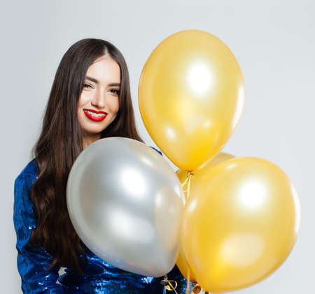 Smiling woman in sequins dress holding balloons portraitの写真素材