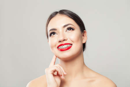 Young woman in braces smiling and looking up on whiteの写真素材