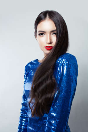 Portrait of pretty woman with long hair and red lips makeup against white wallの写真素材