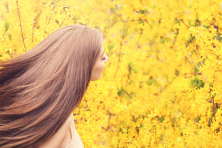 Perfect young woman against yellow flowersの写真素材