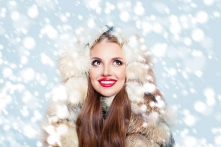 Pretty woman in fur coat on winter snow backgroundの写真素材